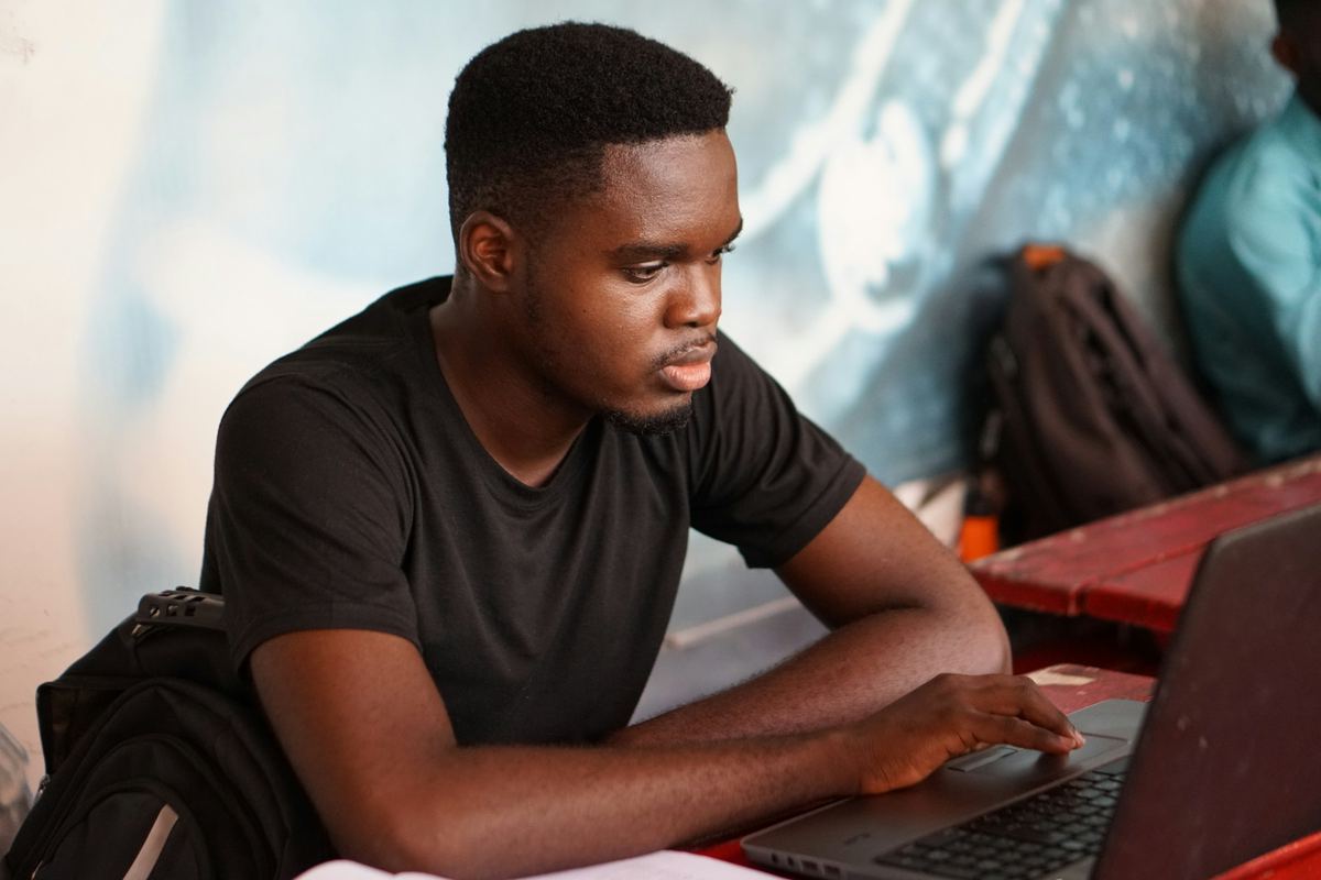A student working on a laptop in a lecture hall in Ghana